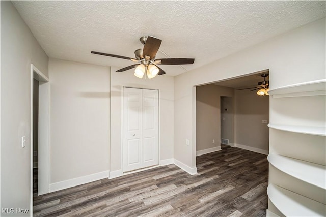 unfurnished bedroom with ceiling fan, a closet, dark hardwood / wood-style flooring, and a textured ceiling