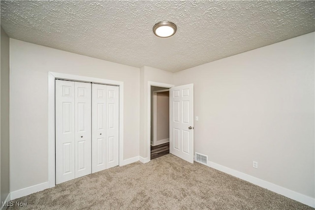 unfurnished bedroom with carpet, a textured ceiling, and a closet