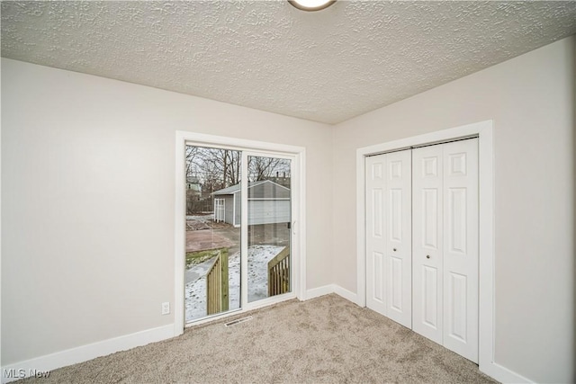 unfurnished bedroom with light carpet, a closet, and a textured ceiling