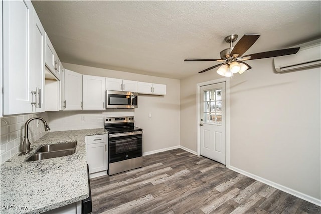 kitchen with sink, dark hardwood / wood-style floors, stainless steel appliances, white cabinets, and light stone countertops