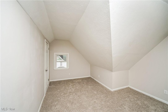 additional living space featuring a textured ceiling, light carpet, and lofted ceiling