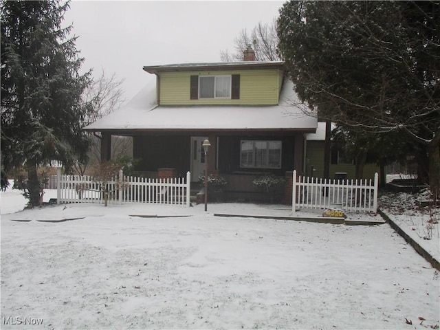 view of front of home featuring a porch, fence, and a chimney