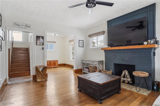 living room with a textured ceiling, ceiling fan, plenty of natural light, and wood-type flooring