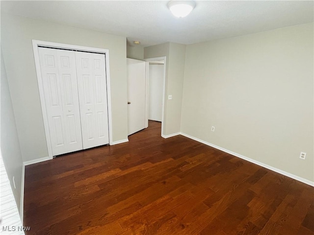 unfurnished bedroom featuring dark hardwood / wood-style floors and a closet