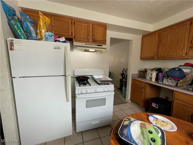 kitchen with light tile patterned floors, white appliances, and a textured ceiling