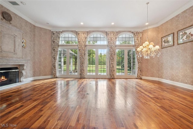 unfurnished living room with crown molding, an inviting chandelier, wood-type flooring, and a premium fireplace