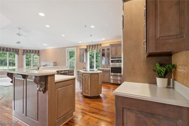 kitchen with a center island with sink, crown molding, a breakfast bar area, and a healthy amount of sunlight