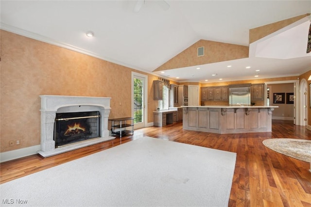 unfurnished living room with light wood-type flooring, lofted ceiling, and crown molding