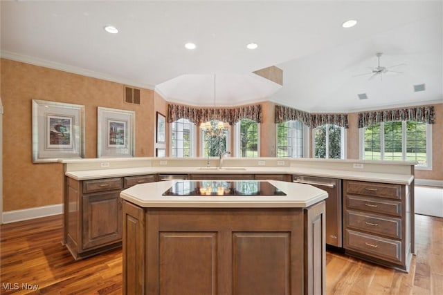 kitchen featuring black electric cooktop, sink, kitchen peninsula, and a kitchen island