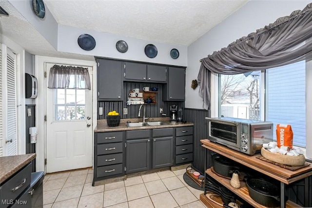 kitchen with gray cabinets, light tile patterned floors, sink, and a textured ceiling