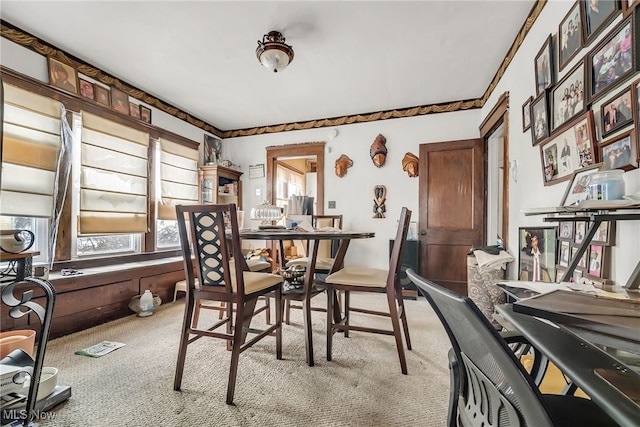 dining area with ornamental molding and light colored carpet