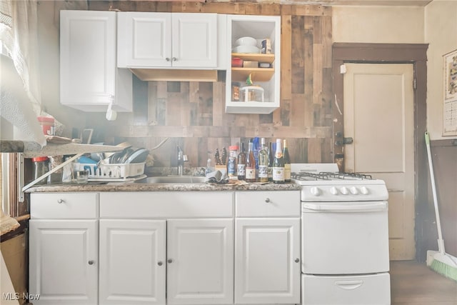 kitchen with tasteful backsplash, white gas range, a sink, and white cabinetry