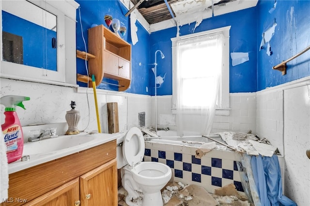 bathroom with tile walls, bathtub / shower combination, toilet, wainscoting, and vanity