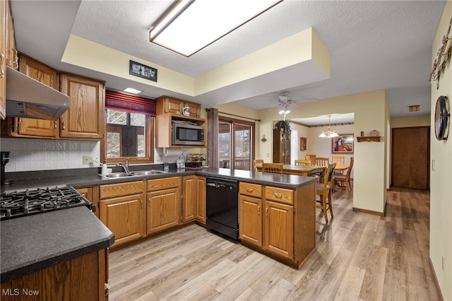 kitchen featuring dishwasher, wall chimney range hood, stainless steel microwave, sink, and kitchen peninsula