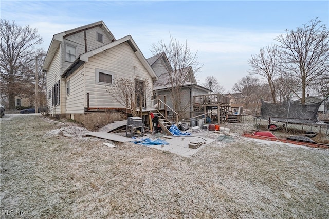 rear view of house featuring a deck and a trampoline