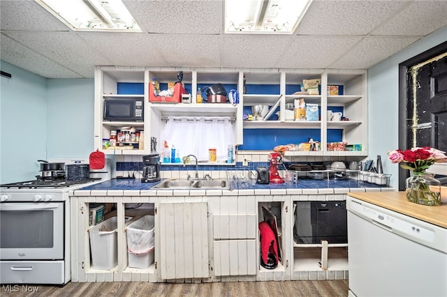 kitchen featuring hardwood / wood-style flooring, sink, white appliances, and tile counters