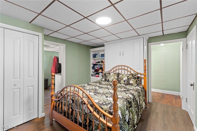 bedroom featuring a closet, wood-type flooring, and a drop ceiling