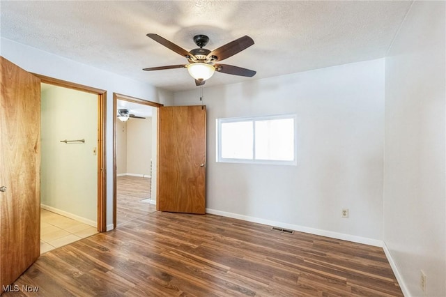 empty room featuring a textured ceiling, hardwood / wood-style floors, and ceiling fan