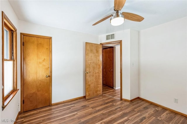 unfurnished bedroom with ceiling fan and dark wood-type flooring