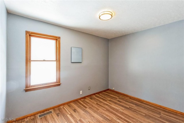 unfurnished room with light wood-type flooring and a textured ceiling