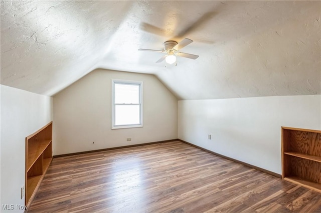 additional living space featuring a textured ceiling, ceiling fan, vaulted ceiling, and dark hardwood / wood-style flooring