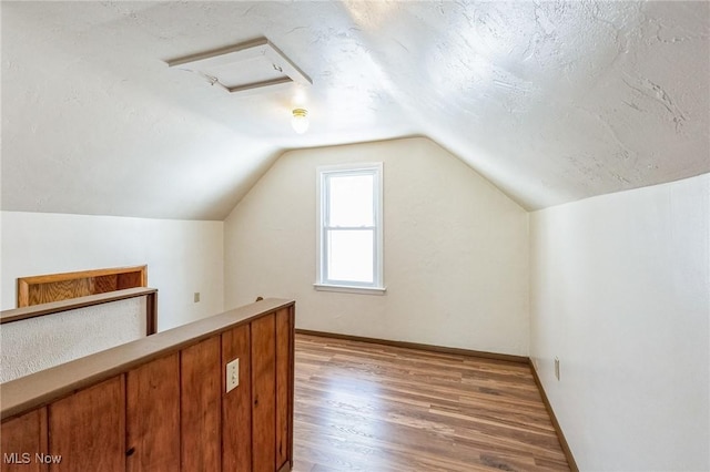 bonus room with lofted ceiling, a textured ceiling, and hardwood / wood-style floors