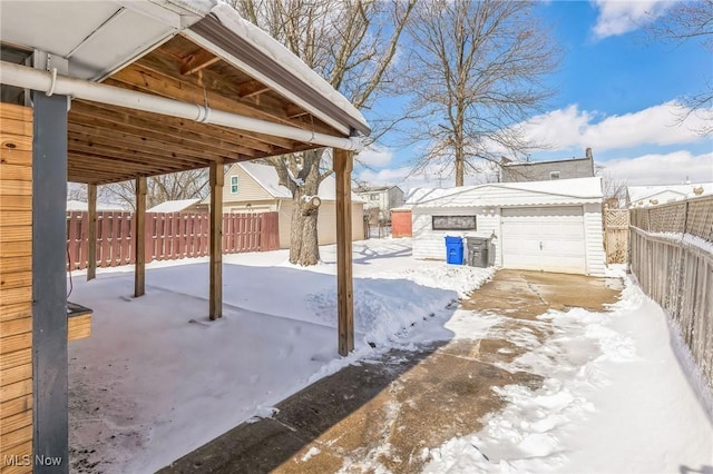 snow covered patio featuring an outbuilding and a garage