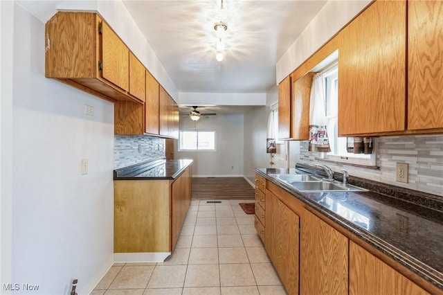 kitchen featuring ceiling fan, light tile patterned flooring, sink, and decorative backsplash