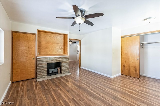 unfurnished living room featuring a brick fireplace, hardwood / wood-style flooring, and ceiling fan