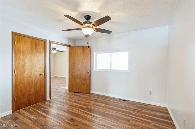 spare room with a textured ceiling, ceiling fan, and dark hardwood / wood-style flooring