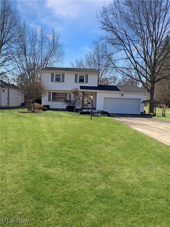 traditional-style house with an attached garage, driveway, and a front lawn