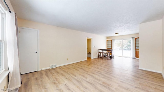 unfurnished room with a textured ceiling and light hardwood / wood-style floors