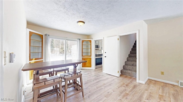 dining room with light hardwood / wood-style flooring and a textured ceiling