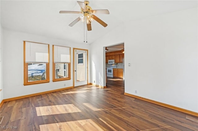 unfurnished room featuring dark wood-style flooring, vaulted ceiling, baseboards, and ceiling fan