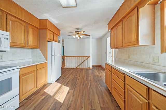 kitchen with dark wood-type flooring, white appliances, light countertops, and backsplash