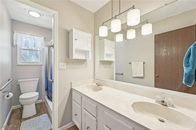 bathroom featuring double vanity, toilet, an enclosed shower, a sink, and wood finished floors