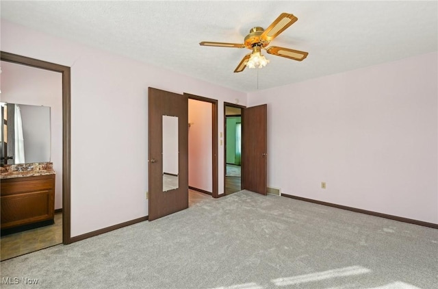 unfurnished bedroom with light carpet, ceiling fan, connected bathroom, and baseboards