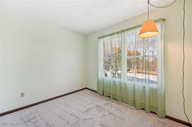empty room featuring a textured ceiling, a healthy amount of sunlight, baseboards, and light colored carpet