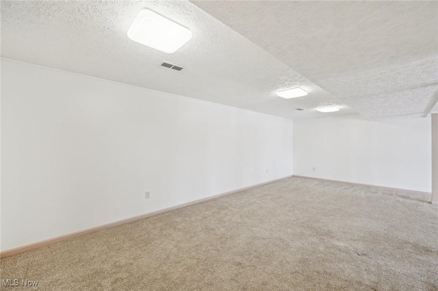 carpeted empty room with visible vents and a textured ceiling