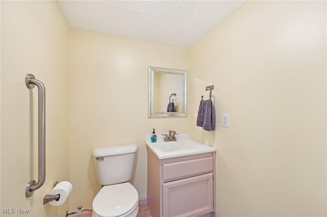 bathroom featuring toilet, a textured ceiling, and vanity