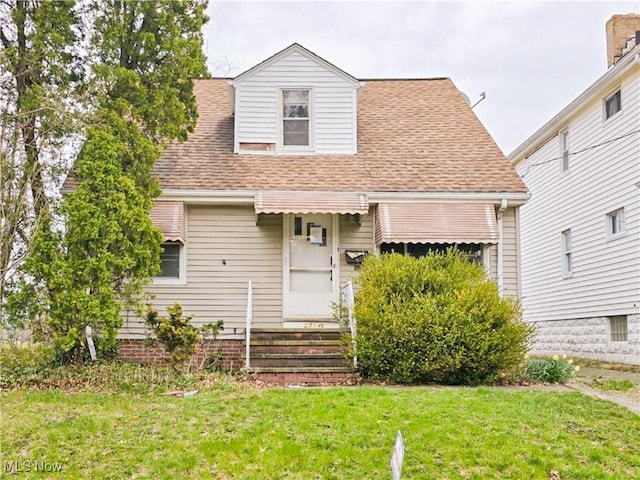 view of front of house with a front lawn and roof with shingles