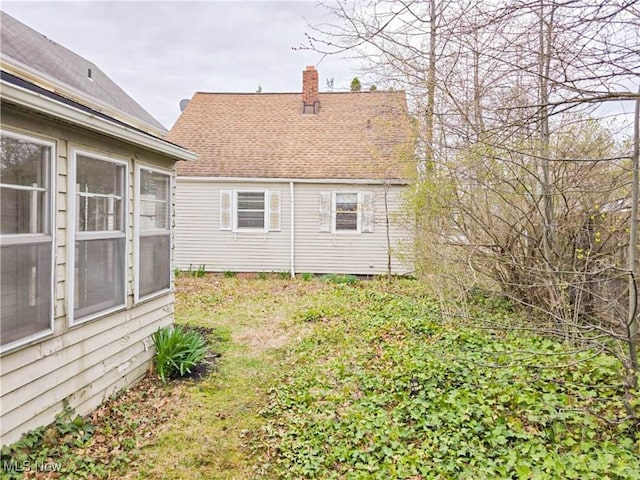 back of property featuring a shingled roof and a chimney
