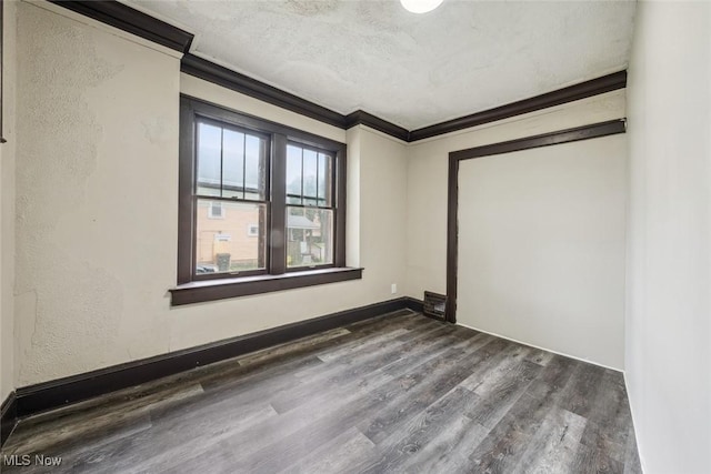 spare room featuring ornamental molding, dark hardwood / wood-style floors, and a textured ceiling