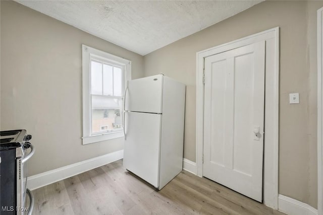 kitchen featuring white fridge, light hardwood / wood-style flooring, stainless steel range oven, and a textured ceiling