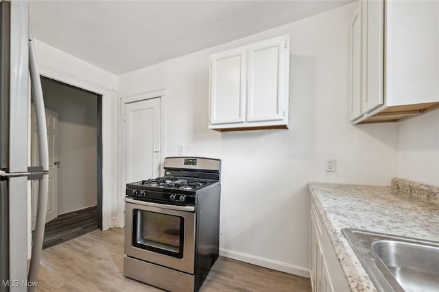 kitchen with white cabinets, light hardwood / wood-style floors, and appliances with stainless steel finishes