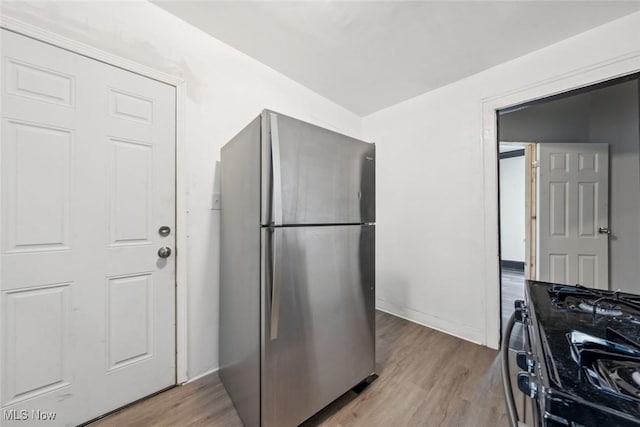 kitchen featuring light wood-type flooring, stainless steel refrigerator, and gas range oven