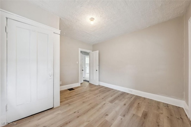 unfurnished bedroom featuring light wood-type flooring, a textured ceiling, and a closet