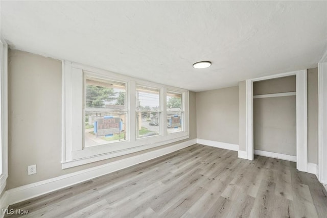 unfurnished bedroom with light hardwood / wood-style flooring, a textured ceiling, and a closet