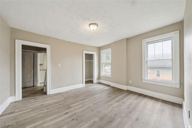 unfurnished bedroom featuring light hardwood / wood-style flooring, a closet, and a textured ceiling