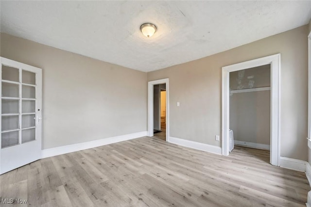 unfurnished bedroom with light hardwood / wood-style flooring, a textured ceiling, and a closet